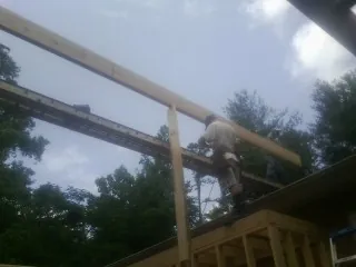 Carpenter setting a ridge beam over a new addition frame — Ice Dam Removal by Roofing Brothers in Kountze