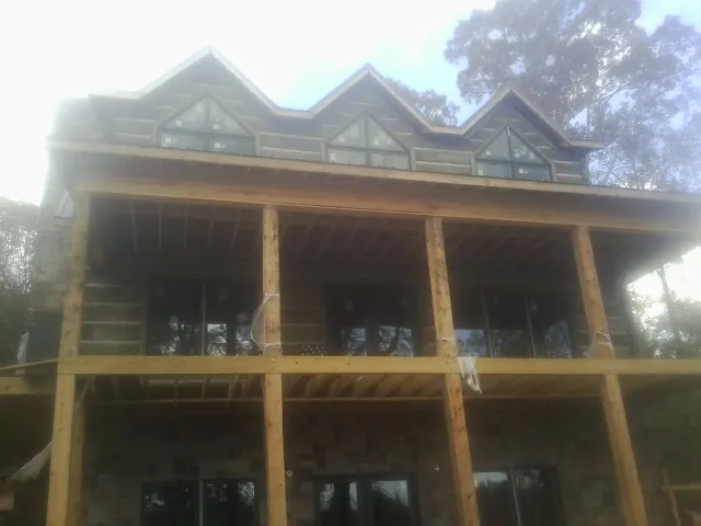 Dormers and porch framing on a large log home under construction — Roof Coating work by our crew in Kountze