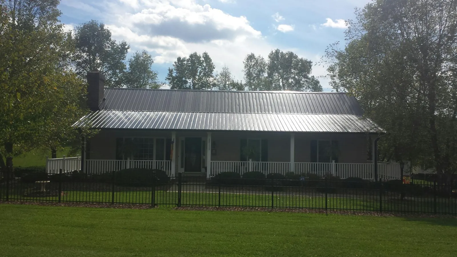 Gray metal roof on a brick ranch with a full width front porch — Gutter Guard Installation work by our crew in Kountze