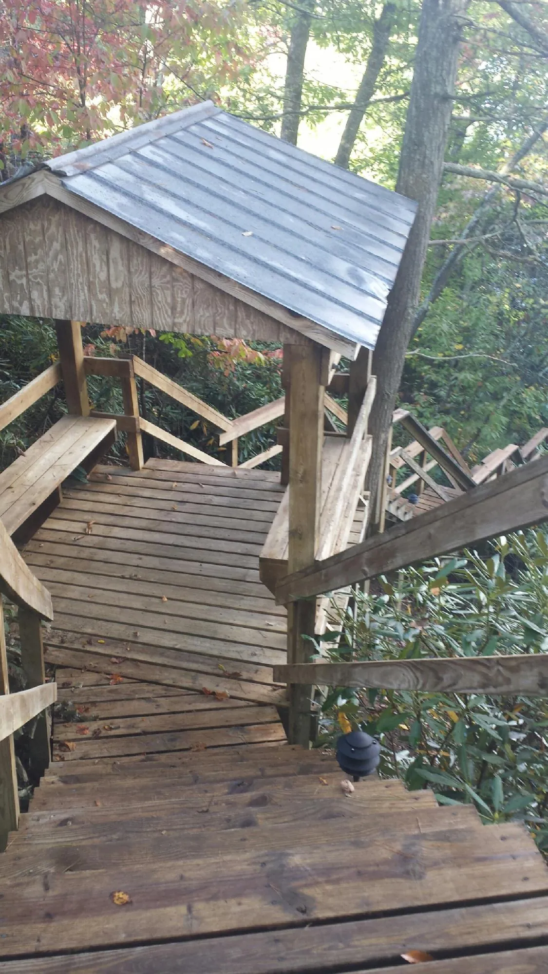 Metal roofed shelter over wooden steps on a wooded walkway — Skylight Repair & Installation work by our crew in Kountze