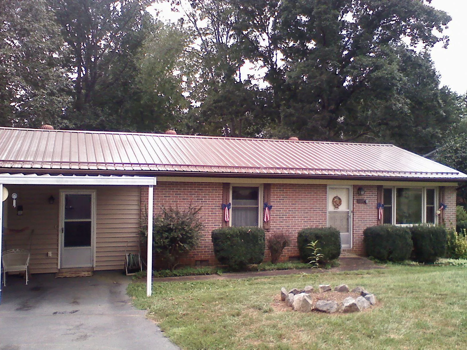 Bronze metal roof and carport on a brick ranch home — Roof Repair work by our crew in Kountze
