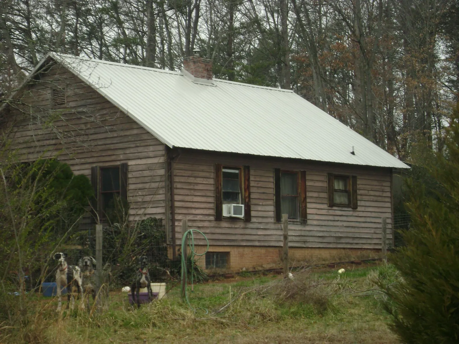 White metal roof on an old wood sided farmhouse, from a Metal Roof Installation job in Kountze