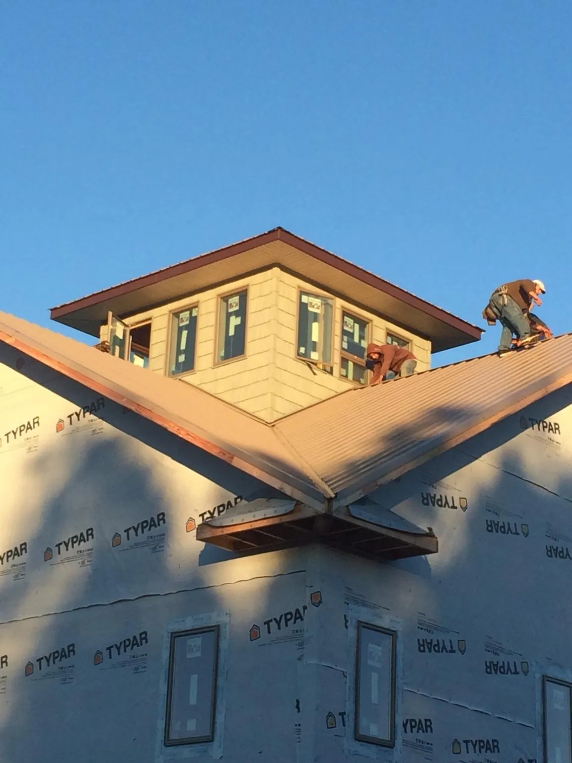 Roofers working around a rooftop cupola on a new metal roof at sunset — Roof Waterproofing in Kountze by Roofing Brothers